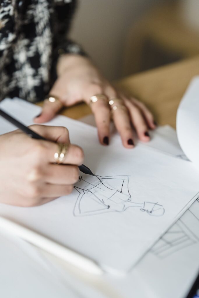 Crop designer drawing female figure on paper